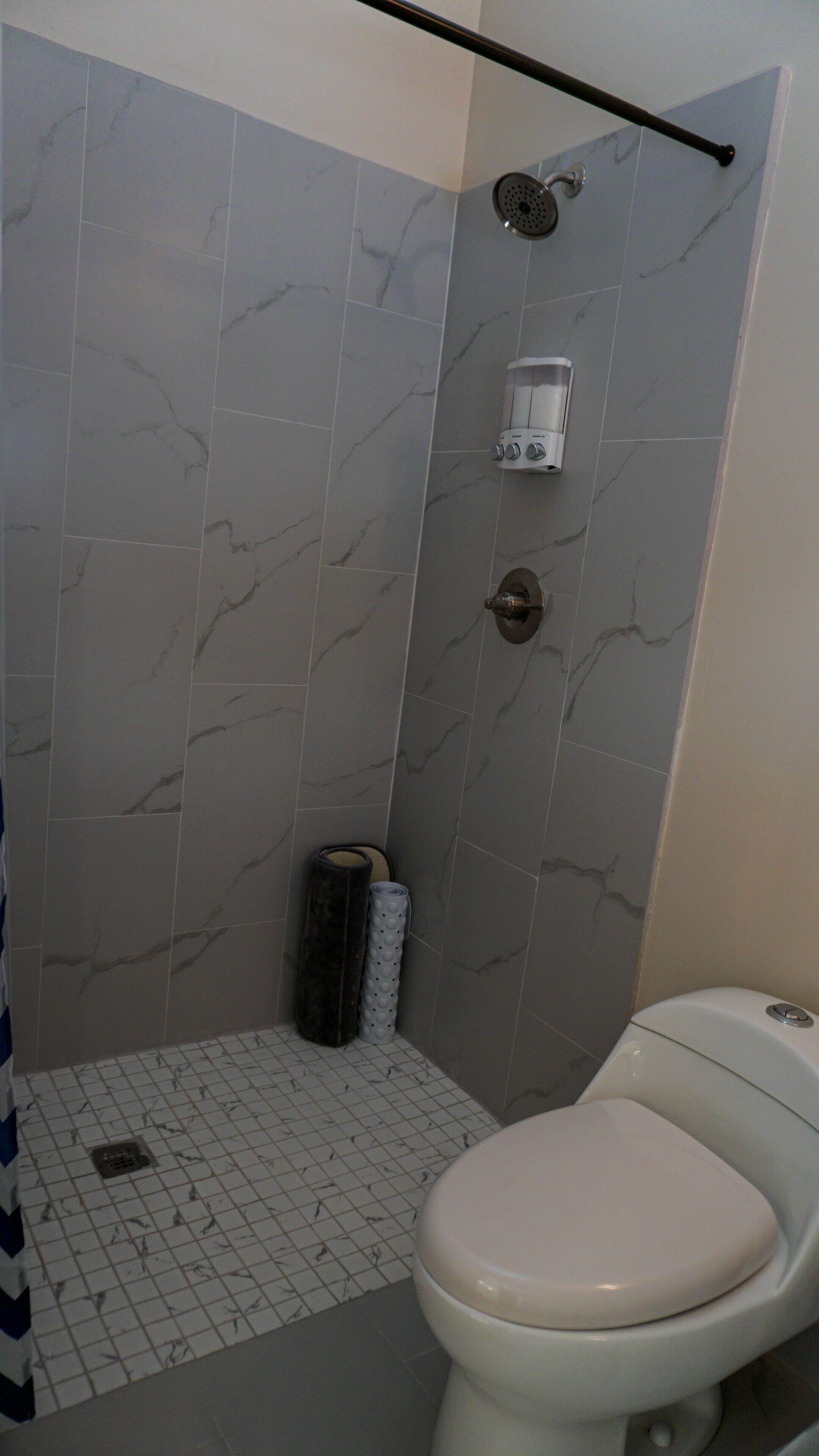 Un baño con ducha, inodoro y dispensador de toallas.