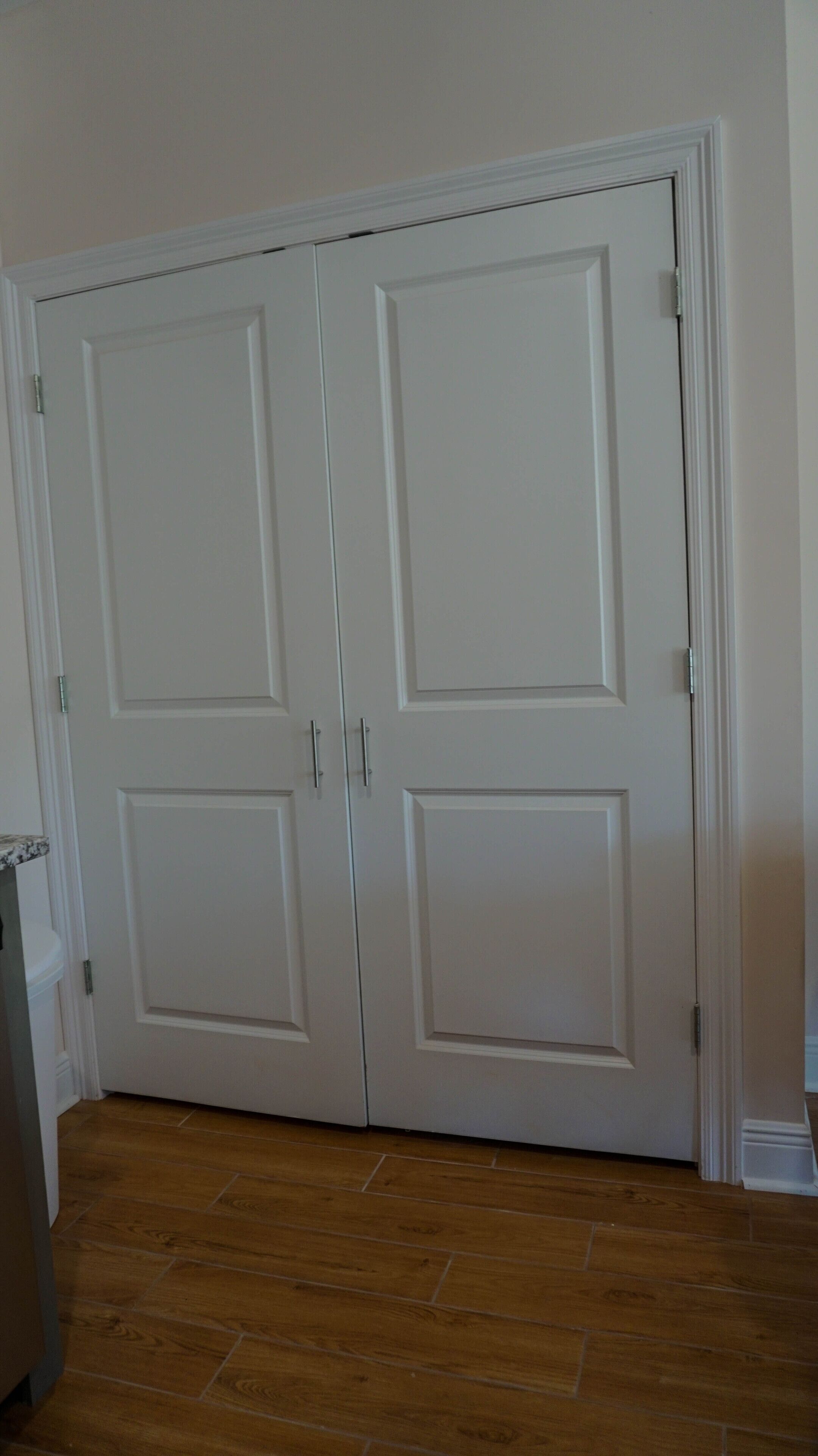A closed white door with a handle, a wooden floor, and a white baseboard.