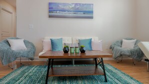 A modern living room with a sofa, two armchairs, a coffee table, and a painting of a beach scene. - 🔥WALK 2 BEACH❤️ | SLEEPS 6 W/ W+D (Biloxi)