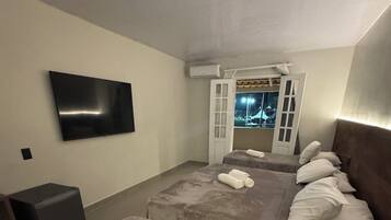 A hotel room with two beds, a flat-screen TV, and a window with a view of the outside.
