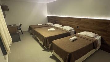 Een hotelkamer met twee bedden, een bureau en een stoel.