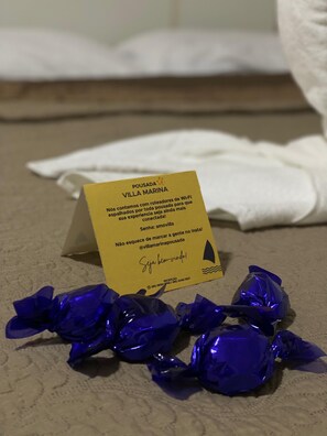 A hotel room with a yellow sign on the floor, a white towel, and blue wrapped items. - Hotel Pousada Villa Marina (Fortaleza)