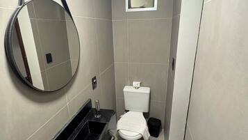 Un baño pequeño y moderno con inodoro, lavamanos y espejo.