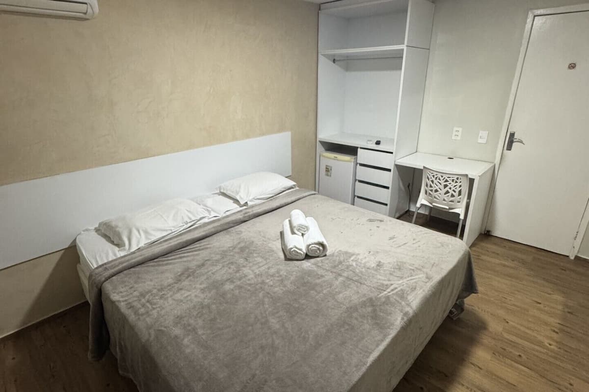 Ein Schlafzimmer mit einem Bett, einem Kleiderschrank, einem Spiegel und einer Tür.