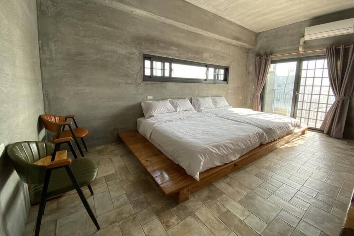 A bedroom with a large bed, a wooden bench, and a chair.