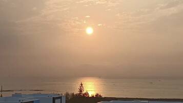A sunset over a body of water with a clear horizon and a distant shoreline.