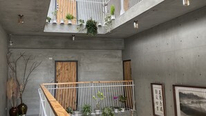 A multi-level interior with concrete walls, wooden railings, and potted plants. - Green House Homestay (Magong)