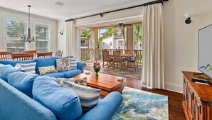 Amplia sala de estar con un sofá azul, una mesa de centro de madera y vistas al área del patio exterior.