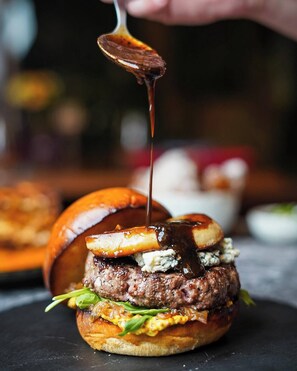 A burger with a sauce being poured over it.