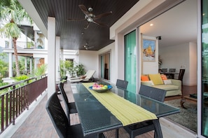 A modern dining area with a glass table, black chairs, and a ceiling fan. - Kata gardens 2 bedroom near Kata beach 3B (Karon)