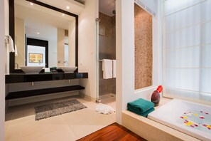 A modern bathroom with a large mirror, two sinks, a shower, and a bathtub.