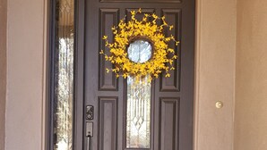 A dark brown front door with a decorative wreath and a small window.