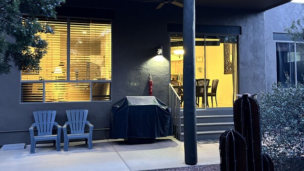 An outdoor patio area with two Adirondack chairs, a covered table, and a cactus.