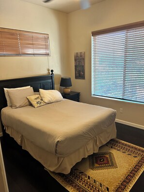 A bedroom with a bed, nightstand, lamp, window with blinds, and a wall-mounted picture. - Sedona Hacienda with Hot Tub, Firepit, Room for 9 and Private Yard. (Sedona)