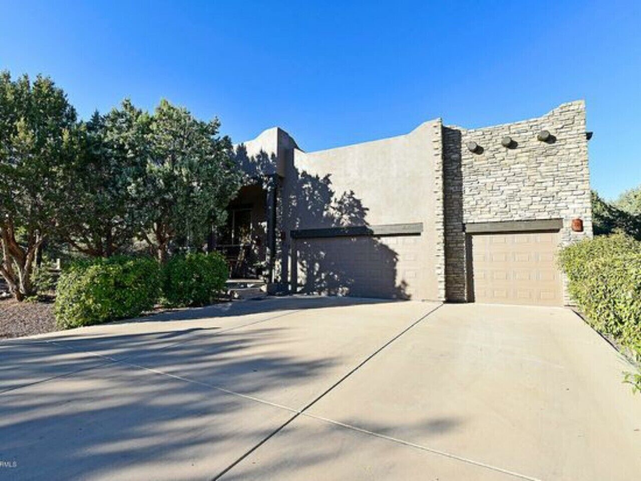 Un bâtiment moderne avec une façade en pierre, un garage et une allée pavée.