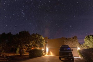 A starry night sky over a residential area with a parked SUV in the foreground and a house with a stone facade. - Sedona Hacienda with Hot Tub, Firepit, Room for 9 and Private Yard. (Sedona)