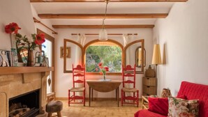 A cozy room with a fireplace, a red sofa, and a dining area with two chairs. - Los Lagos by Interhome (Dénia)