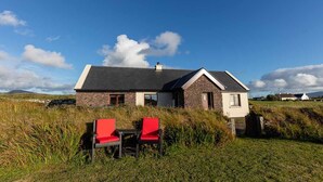 A house with a stone exterior, a pitched roof, and a small attached structure.
