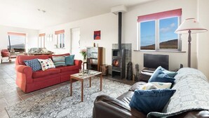 A cozy living room with a fireplace, a red sofa, and a leather couch.