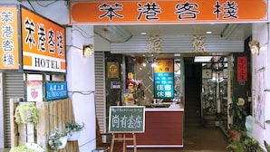 A hotel entrance with a signboard indicating it is a hotel. There are potted plants outside, and a small reception desk with a sign. - Pon Kan Inn (Beigang)