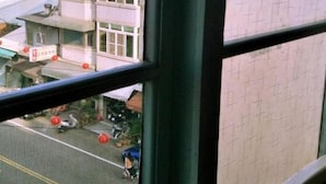 A view from a window of a building with multiple floors, featuring a parking area with vehicles and a small building with a red roof. - Pon Kan Inn (Beigang)