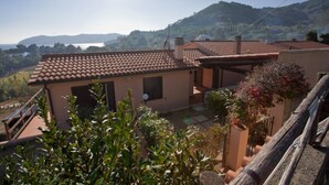A residential building with a tiled roof, a small attached structure, and a garden area with various plants. - APP.TI NORSI - NORSI - MONO (Capoliveri)