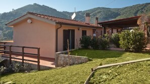 A single-story house with a tiled roof, a stone foundation, and a small garden area. - APP.TI NORSI - NORSI - MONO (Capoliveri)