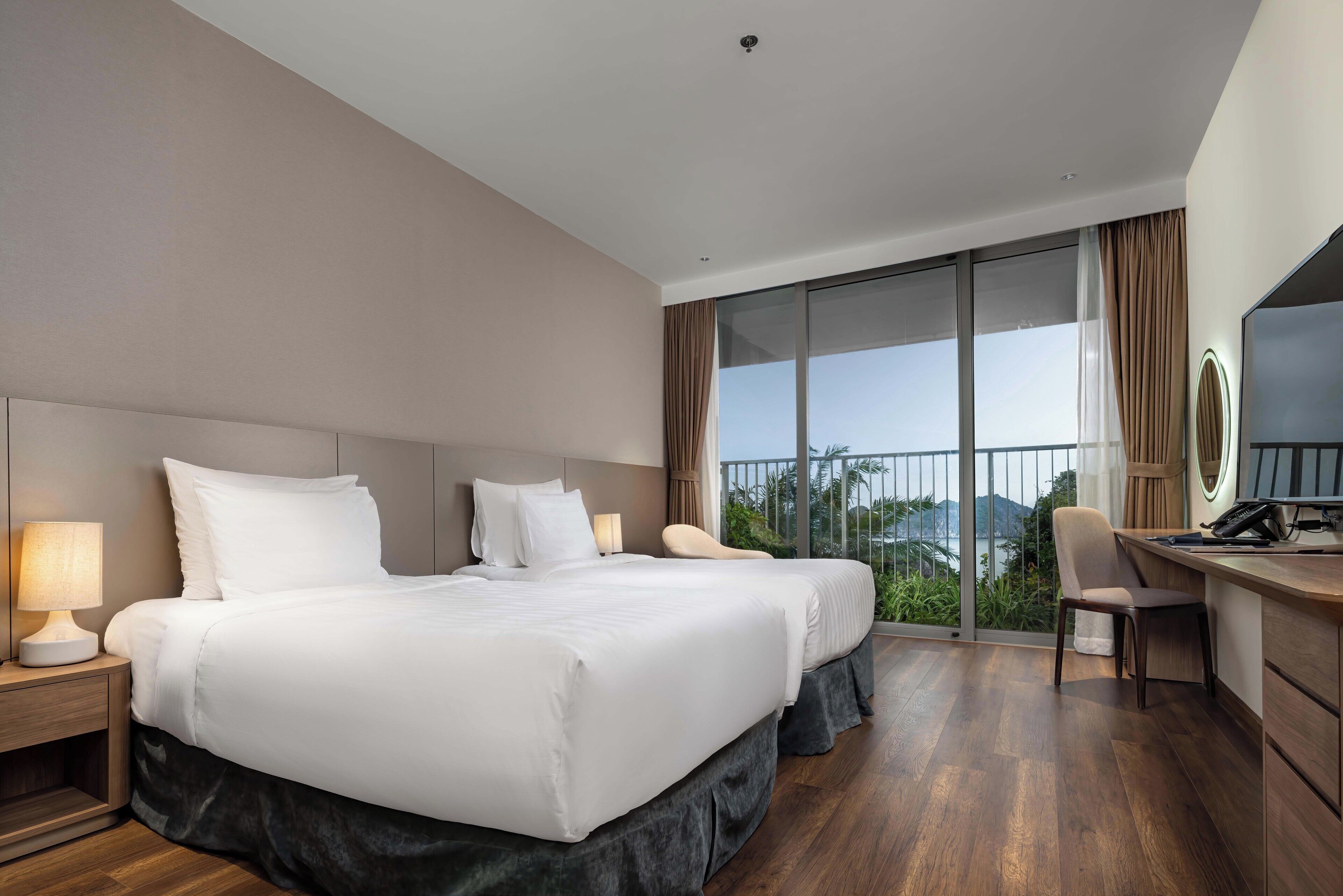 Een hotelkamer met twee bedden, een bureau, een stoel en een groot raam met uitzicht.