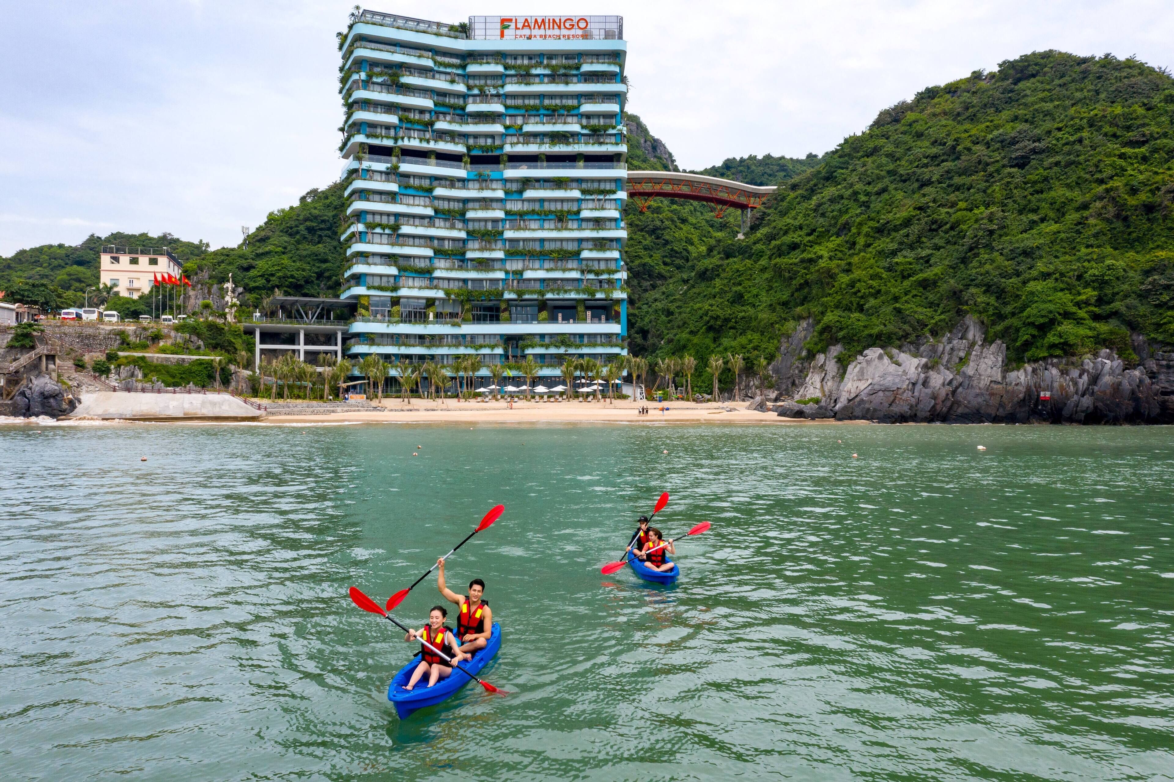 A hotel with multiple balconies, a beach, and kayaks on the water.