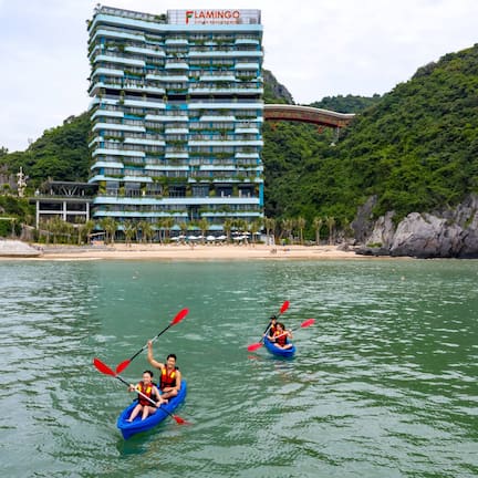 A hotel with multiple balconies, a beach, and kayaks on the water.