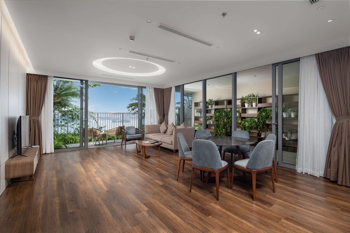 A spacious living room with a wooden floor, a sofa, a dining table with chairs, and a TV.