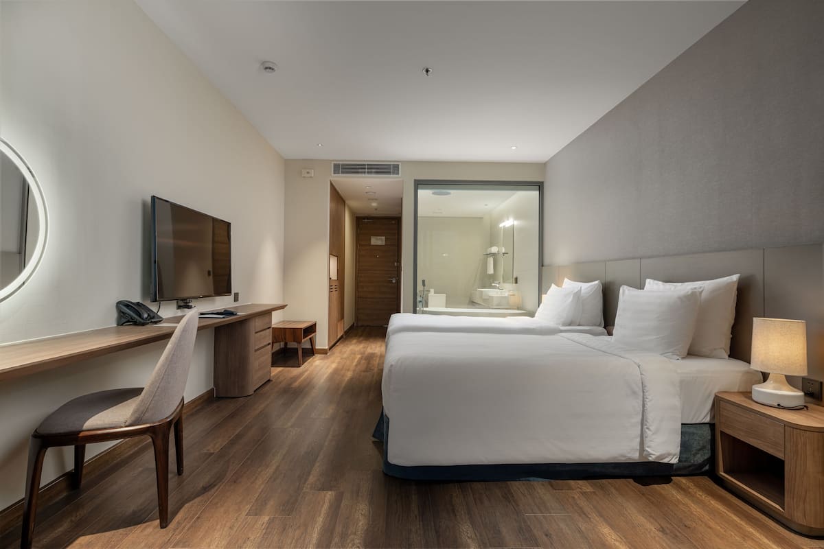 Une chambre d’hôtel comprenant un lit, un bureau avec une chaise, une télévision et une table de chevet avec une lampe.
