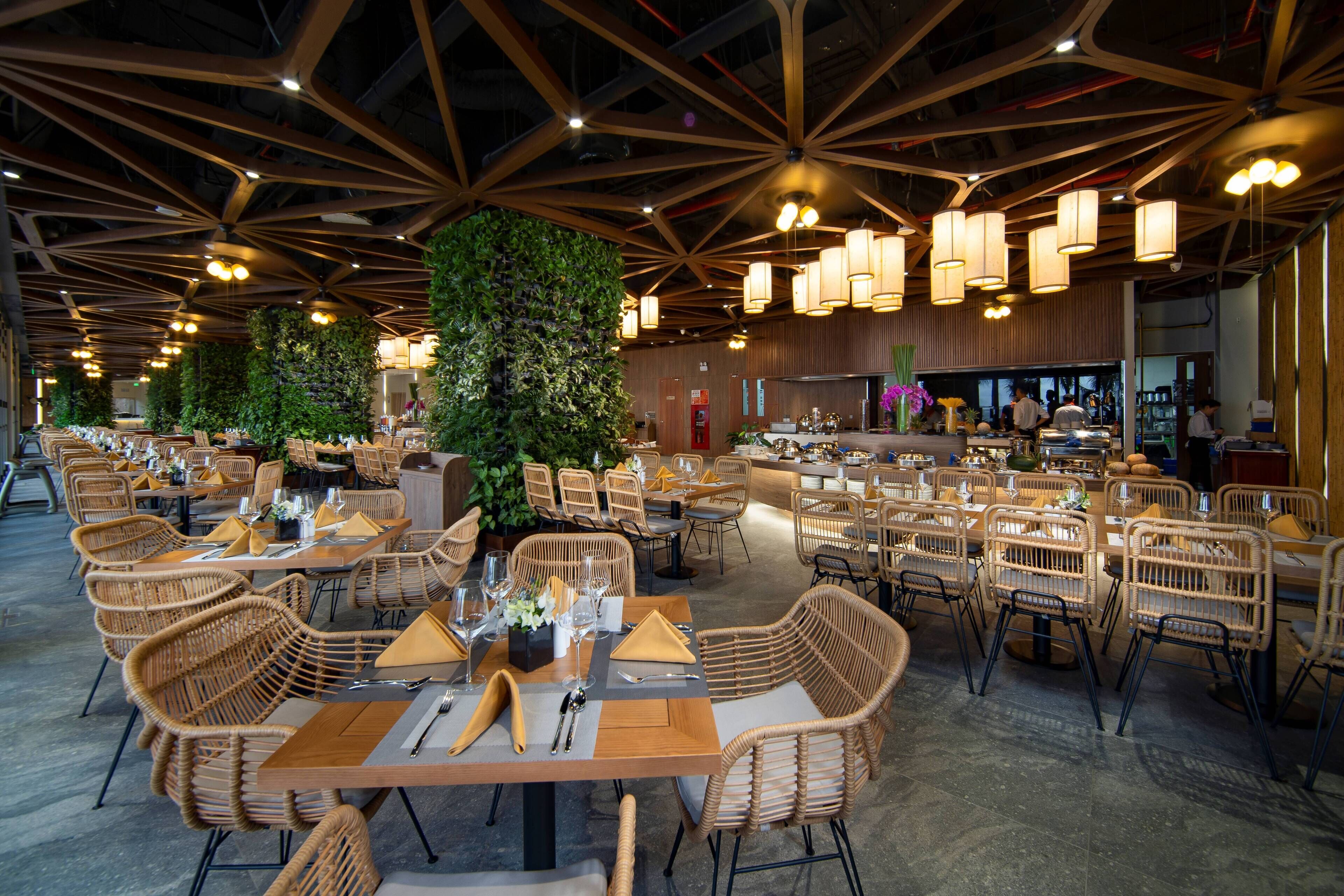 Ein geräumiges Restaurant mit hohen Decken, moderner Beleuchtung und Korbmöbeln.