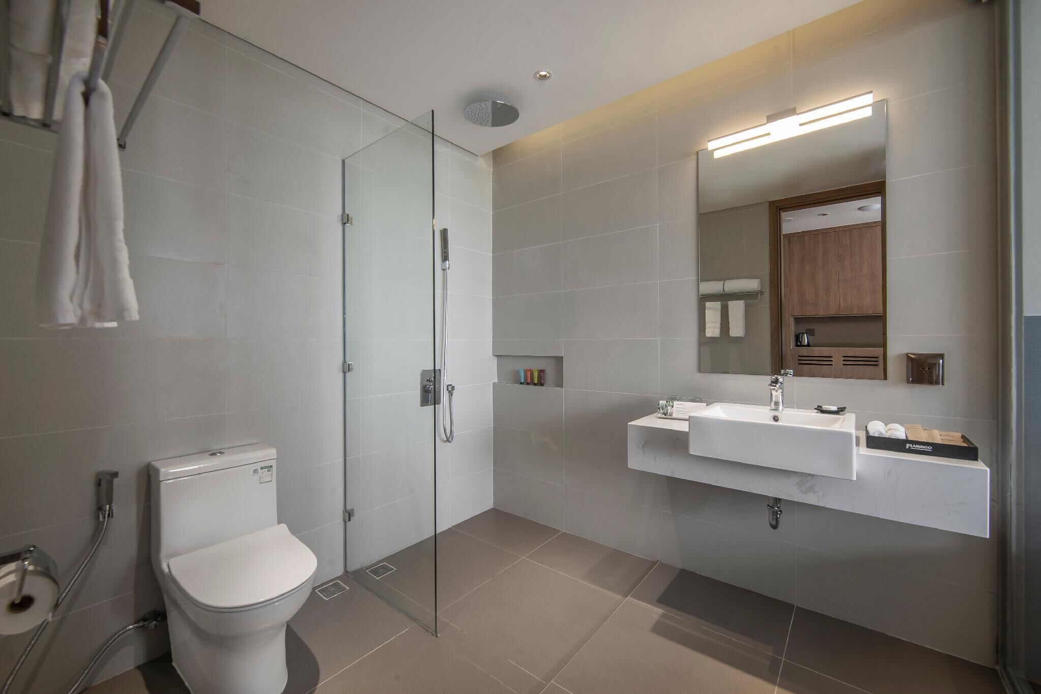 Une salle de bain moderne avec une douche à parois de verre, des toilettes blanches et un meuble-lavabo avec un miroir et un évier.