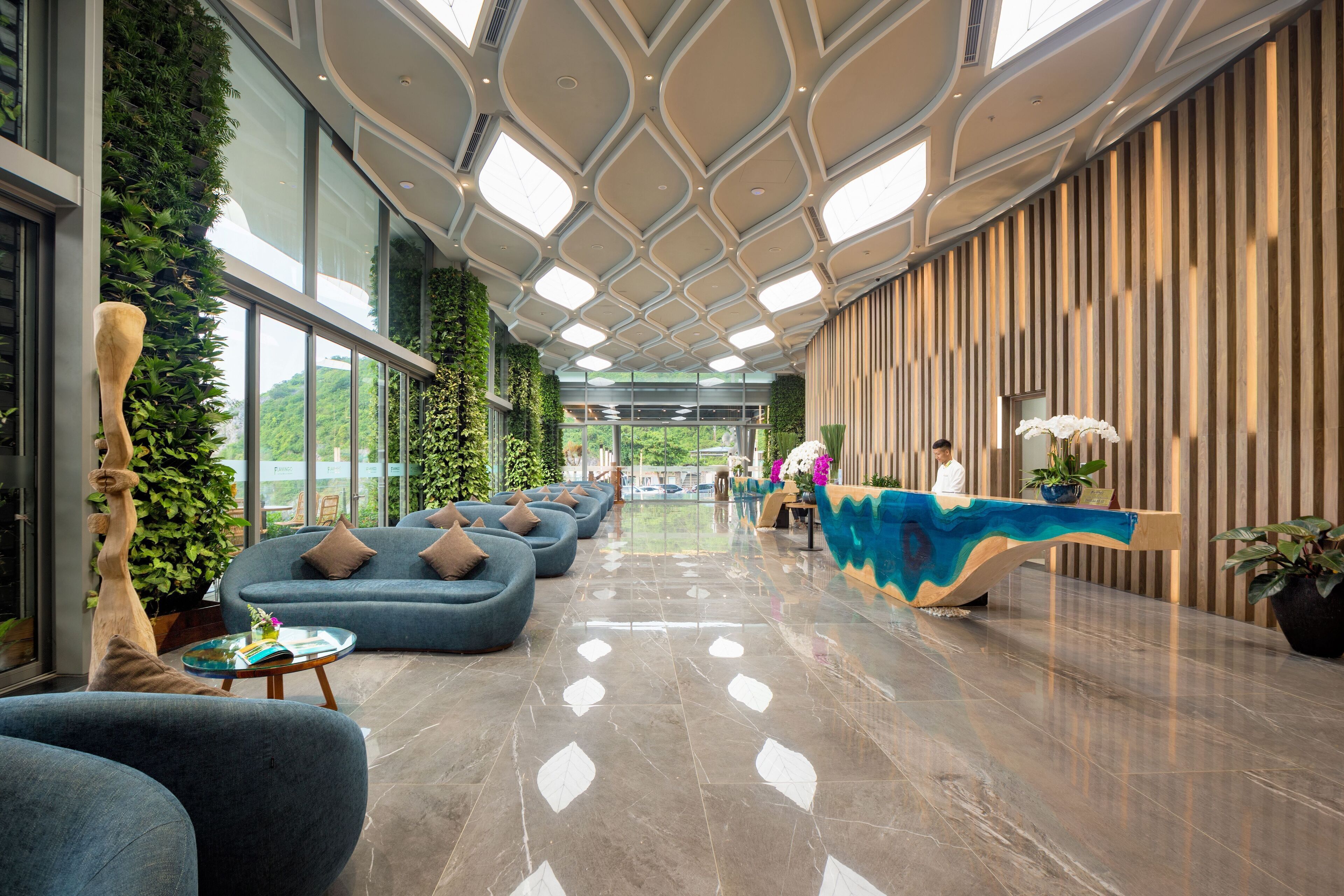 A modern lobby with a reception desk, blue sofas, and a green wall.