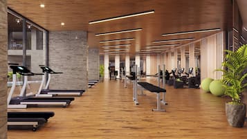 Un gimnasio moderno con cintas de correr, máquinas de pesas y piso de madera.