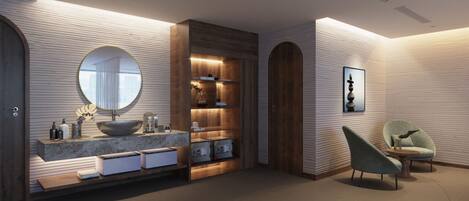 A modern bathroom with a large round mirror, wooden vanity, and a seating area with a chair.