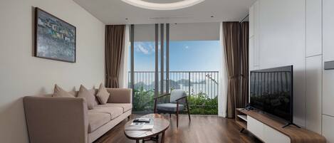 A modern living room with a sofa, a chair, a coffee table, a TV, and a balcony with a view.