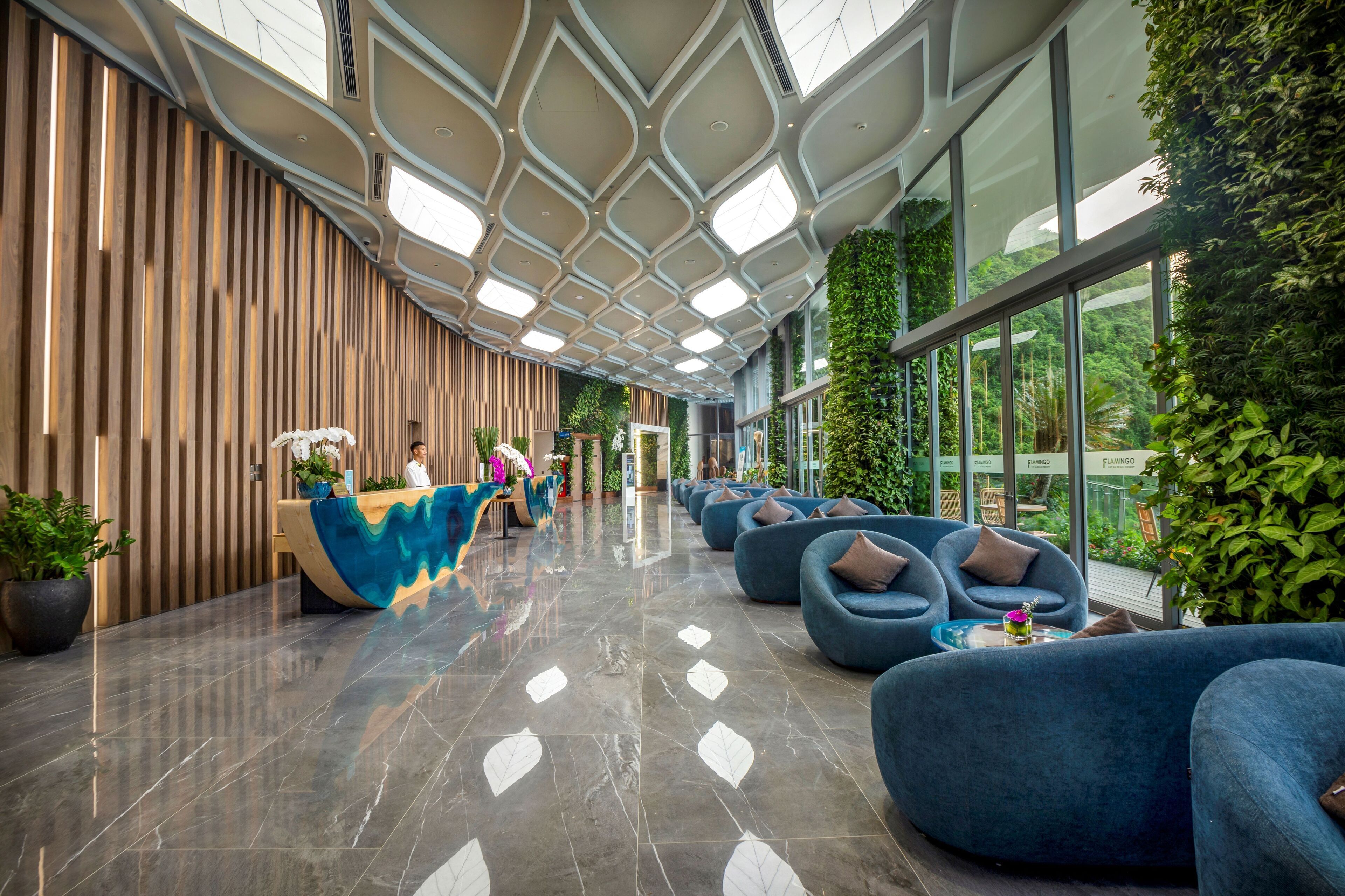 A modern lobby with a reception desk, seating area, and large windows.