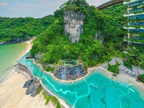 Vista aérea de un resort con un acantilado imponente, una playa y un área de piscina.