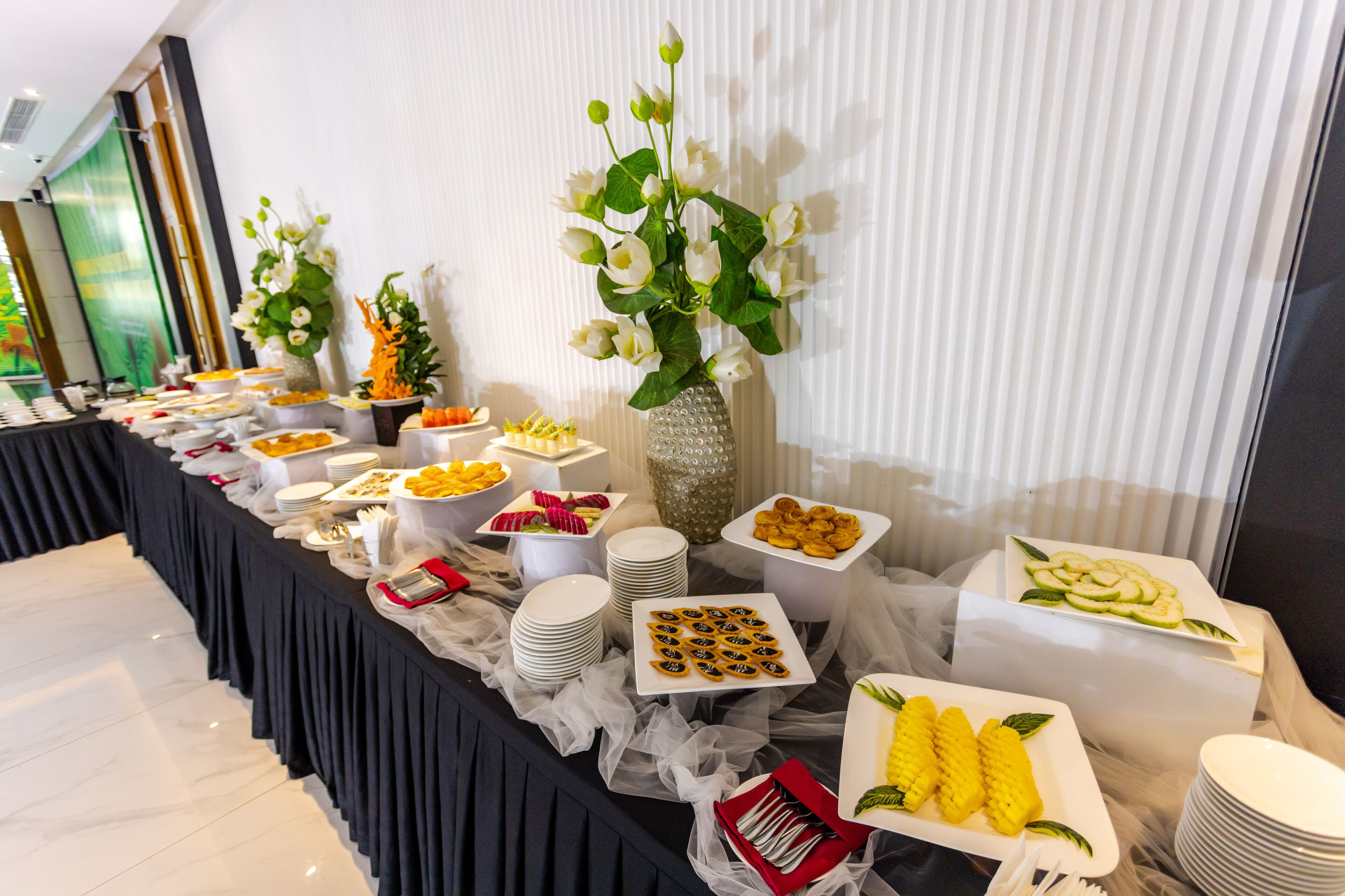 A buffet table with various food items and a decorative vase with flowers.