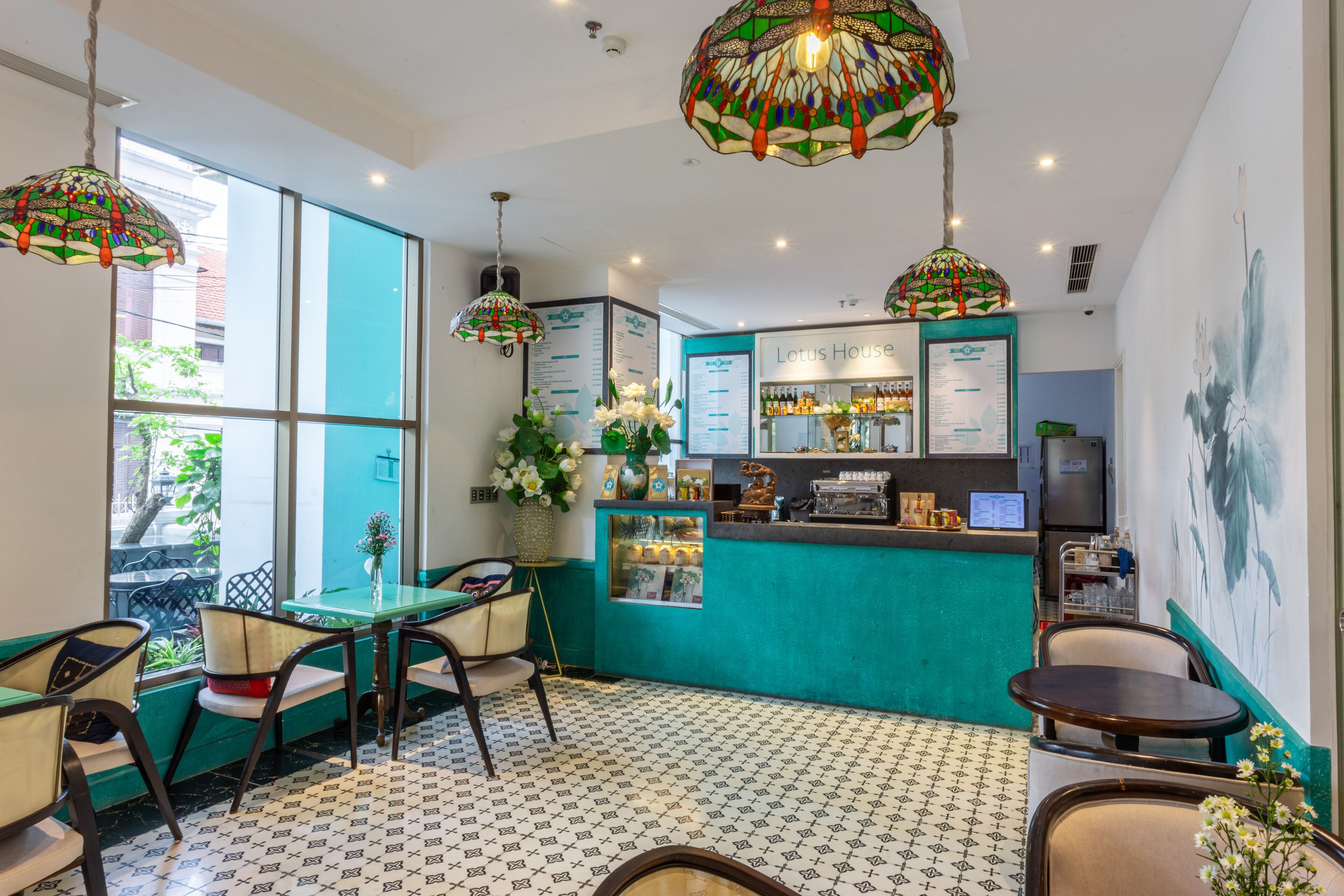 A restaurant with teal walls, patterned floor tiles, and hanging stained glass lamps.