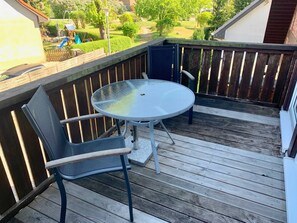 Eine Holzterrasse mit einem runden Glastisch und zwei Stühlen.