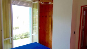 Une chambre avec un lit, une porte en bois et une vue sur un balcon.