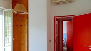 Une pièce avec une porte en bois, une porte rouge et une lampe suspendue.
