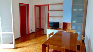 Une pièce avec une table en bois, des chaises, un téléviseur et une bibliothèque.