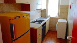 Une cuisine de taille réduite, avec un réfrigérateur jaune, une cuisinière, un évier et un petit réfrigérateur.