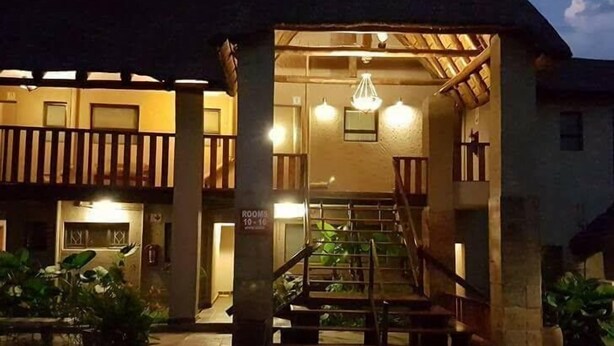 Un edificio con entrada cubierta, una escalera y un cartel que indica 'Rooms 10-15'.