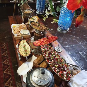 Une table de buffet proposant divers plats, notamment des salades, du riz et des amuse-gueules.