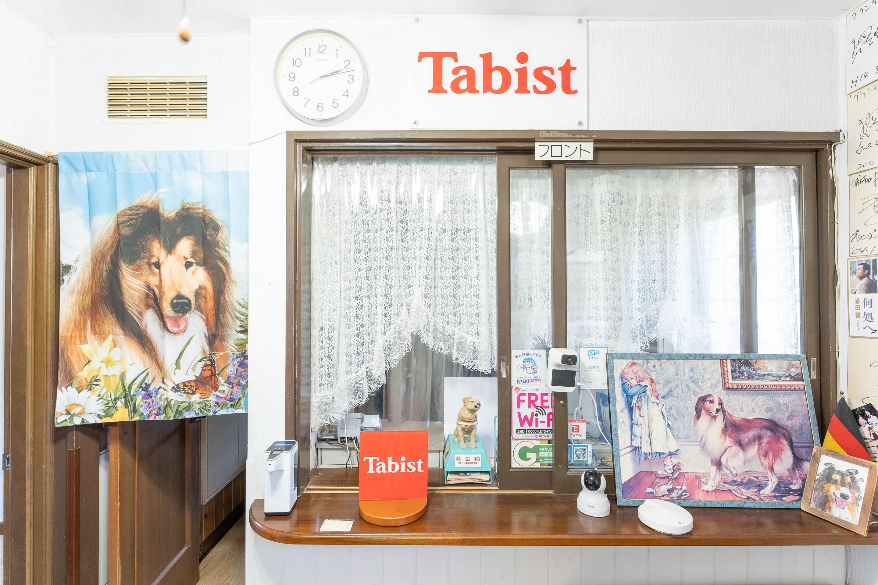A reception desk with a sign reading "Tabist," a clock, and various framed pictures of dogs.